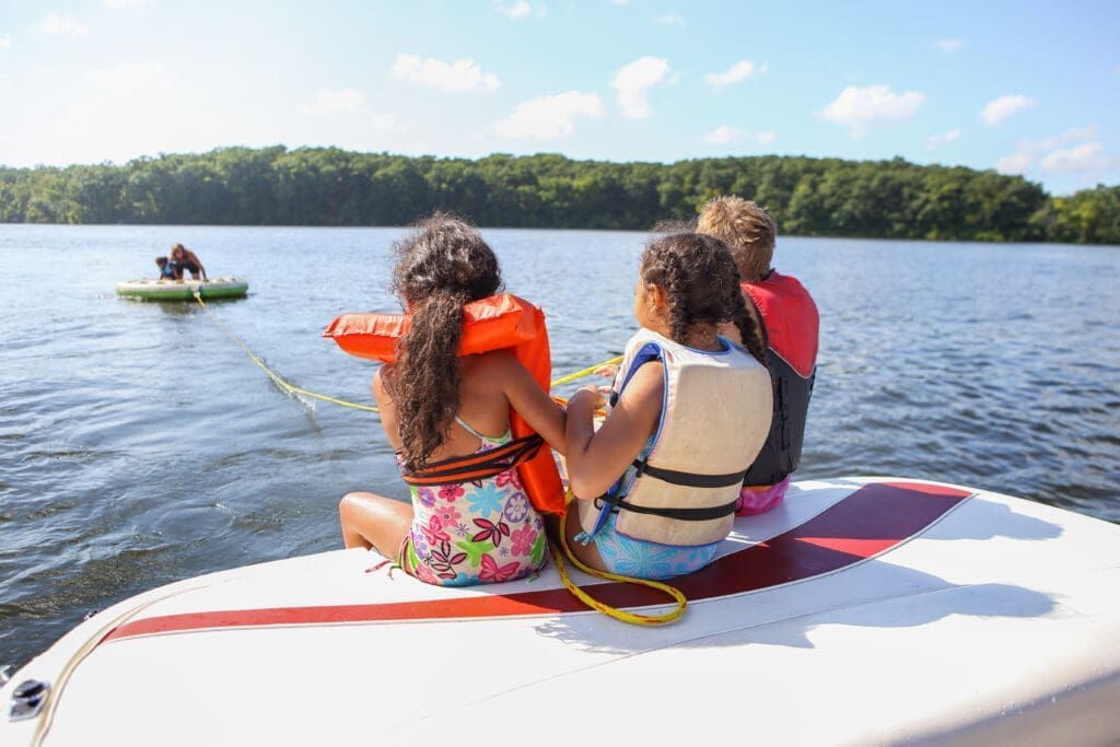 People sitting on a boat and tubing on an inland lake